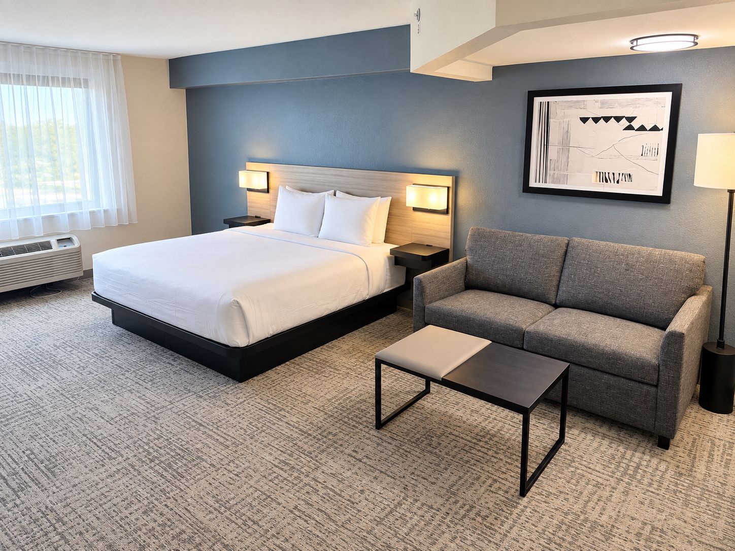 Ein Hotelzimmer mit einem Bett, einem Sofa, einem Couchtisch und einer Wandlampe.