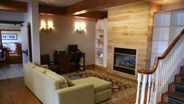 A living room with a sofa, a fireplace, a desk with a computer, and a staircase.