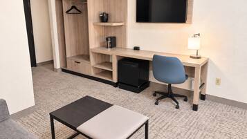 A hotel room with a desk, chair, and a television mounted on the wall.