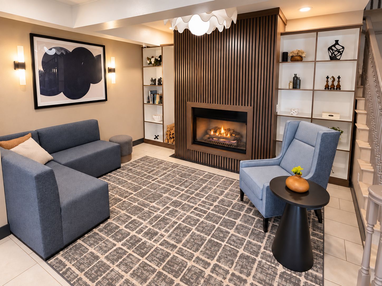 Ein modernes Wohnzimmer mit Kamin, blauen Sofas, einem gemusterten Teppich und einer Treppe.