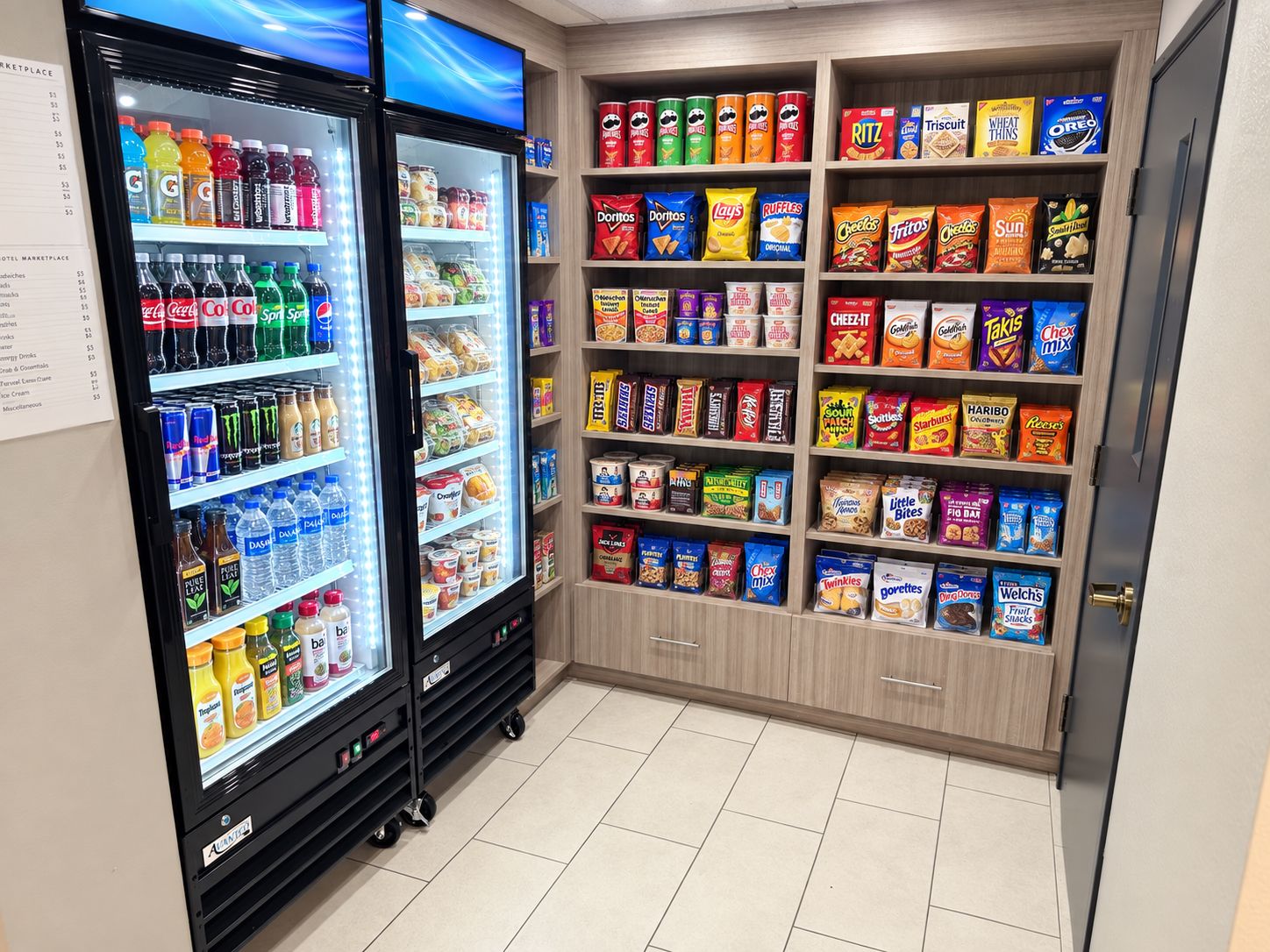 A hotel minibar with a variety of snacks and beverages, including chips, cookies, and bottled drinks.
