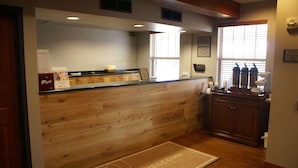 A kitchen with wooden cabinetry, a welcome mat, and a window with blinds.
