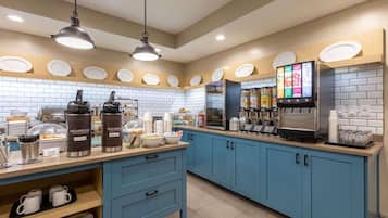 A modern kitchen with blue cabinets, a coffee station, and a menu display.