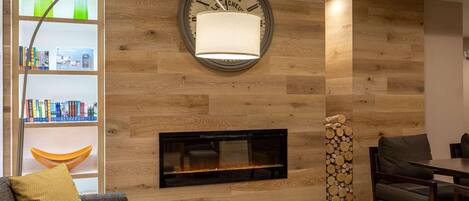 A modern living room with a fireplace, a wooden wall, a bookshelf, and a dining area.