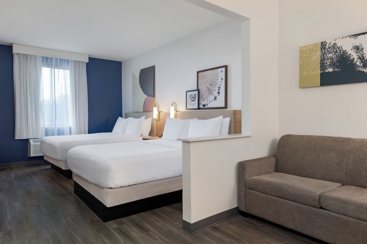 Ein Hotelzimmer mit zwei Betten, einer Schlafcouch und Bildern an den Wänden.