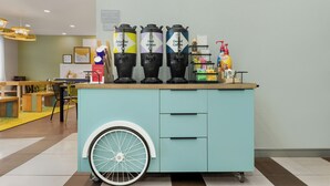 A coffee station with three dispensers labeled Regular Coffee, Hot Water, and Decaf Coffee, and a bottle of hand sanitizer on a counter. - Spark by Hilton Indianapolis Northeast Fishers (Fishers)
