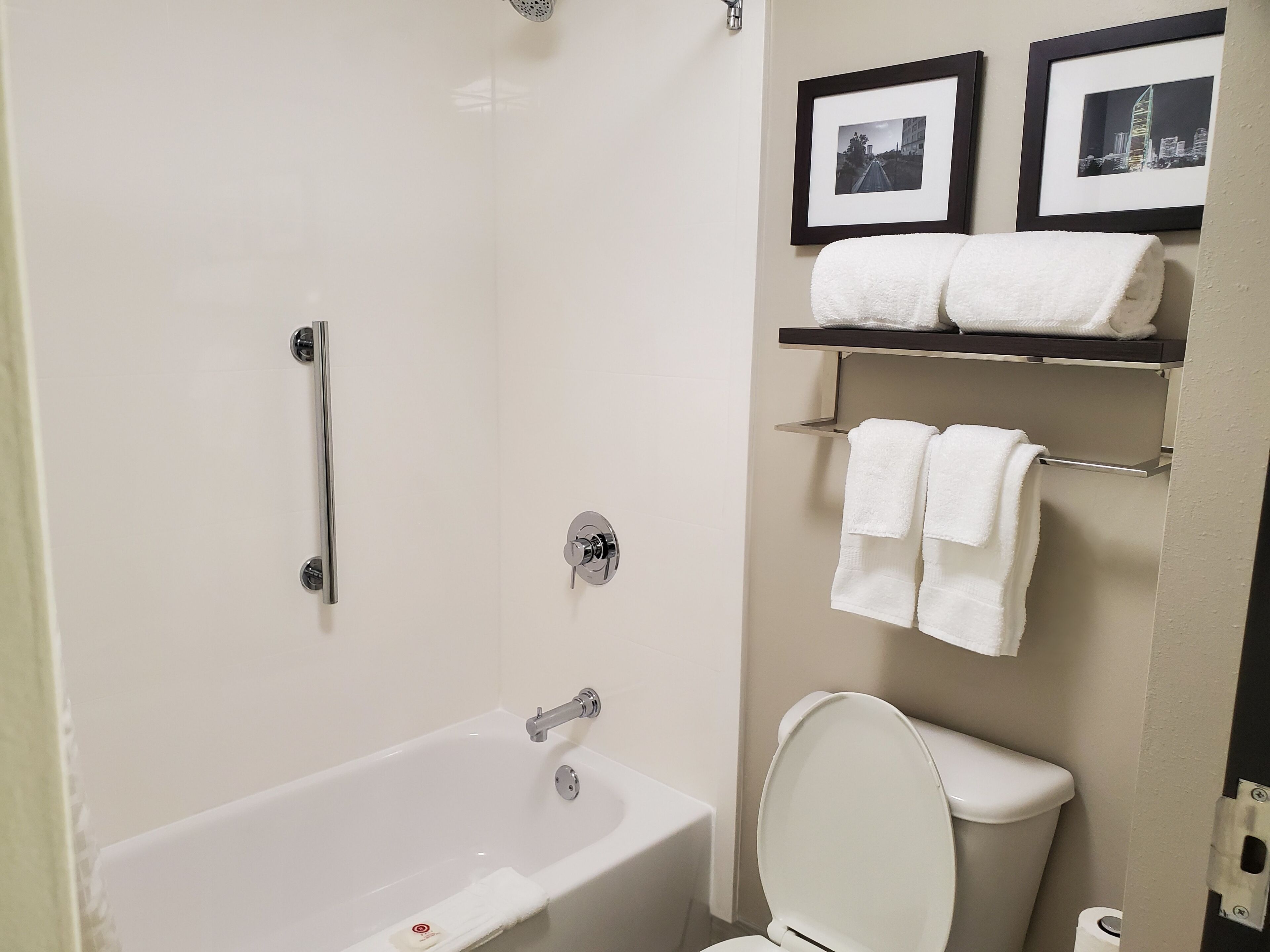 Un baño con bañera, inodoro y dos cuadros en la pared.