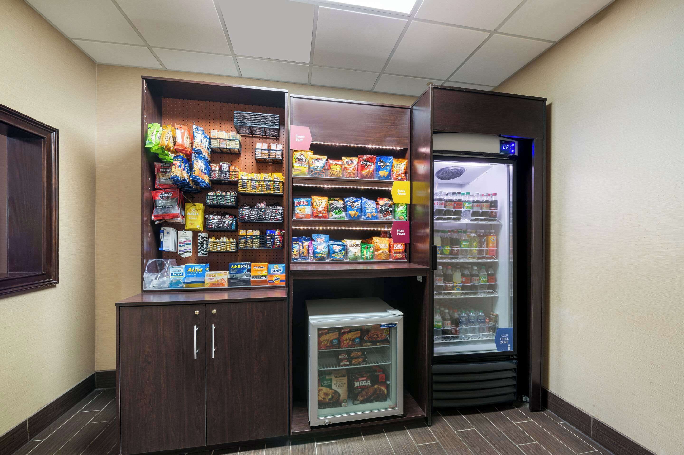 A self-service snack and beverage station with refrigerated and non-refrigerated options, including chips, snacks, and drinks.