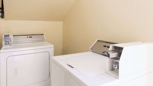 A laundry room with a front-loading washer and dryer, a utility sink, and a towel rack. - Days Inn by Wyndham Rayne/Crowley (Rayne)