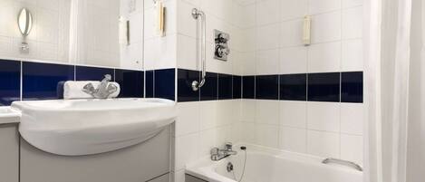 A modern bathroom with a white sink, a bathtub, and a shower area.