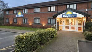 A Days Inn hotel with a brick facade, large windows, and a well-lit entrance. - Days Inn by Wyndham Michaelwood M5 (Berkeley)