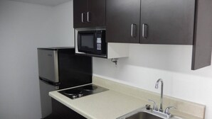 A compact kitchen with a microwave, stove, and sink. - Motel 6 Portland, TX (Portland)