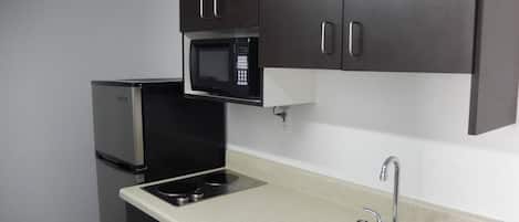 Une cuisine compacte équipée d’un four à micro-ondes, d’une cuisinière et d’un évier.