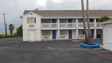 A motel with a two-story structure, multiple rooms with blue doors, and a parking lot.