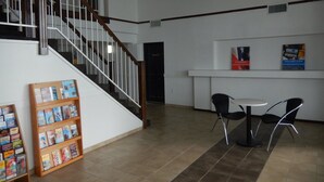 A reception area with a staircase, a bulletin board with magazines, and a counter with chairs. - Motel 6 Portland, TX (Portland)