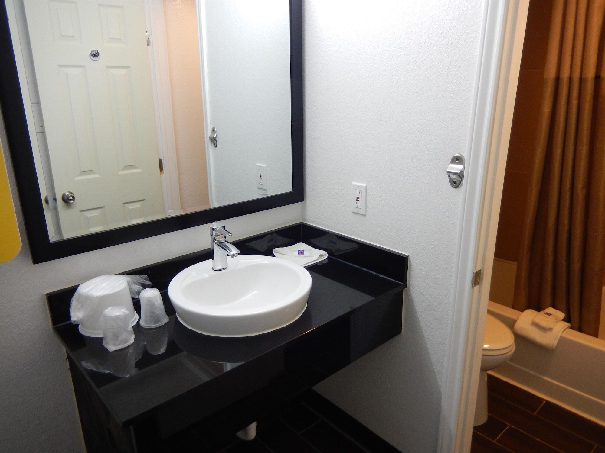 A bathroom with a white sink, black countertop, and a mirror above it.