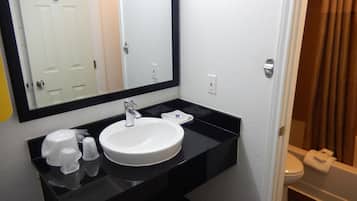 A bathroom with a white sink, black countertop, and a mirror above it.
