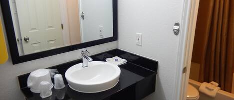 A bathroom with a white sink, black countertop, and a mirror above it.