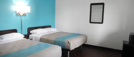 A hotel room with two beds, a blue wall, a white wall, a mirror, and a dark wooden floor.