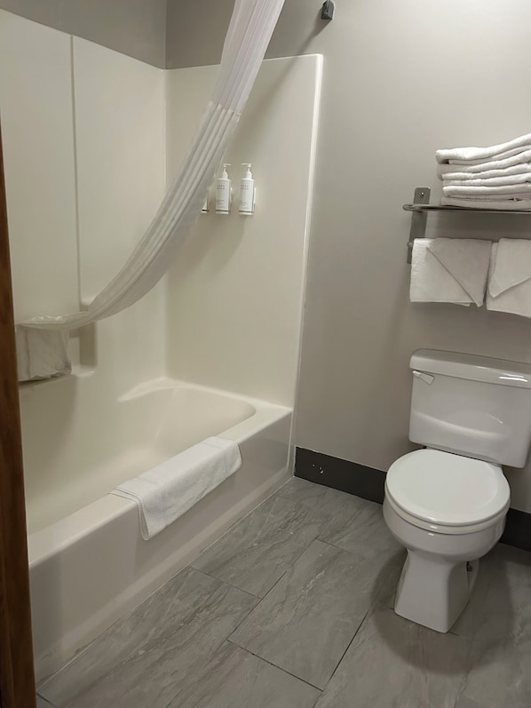 A bathroom with a bathtub, toilet, and a shower curtain. - Days Inn by Wyndham Laramie (Laramie)