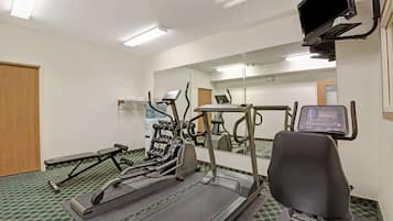 Una palestra con tapis roulant, una panca e uno specchio a parete.
