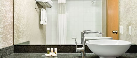 A bathroom with a sink, mirror, and shower.