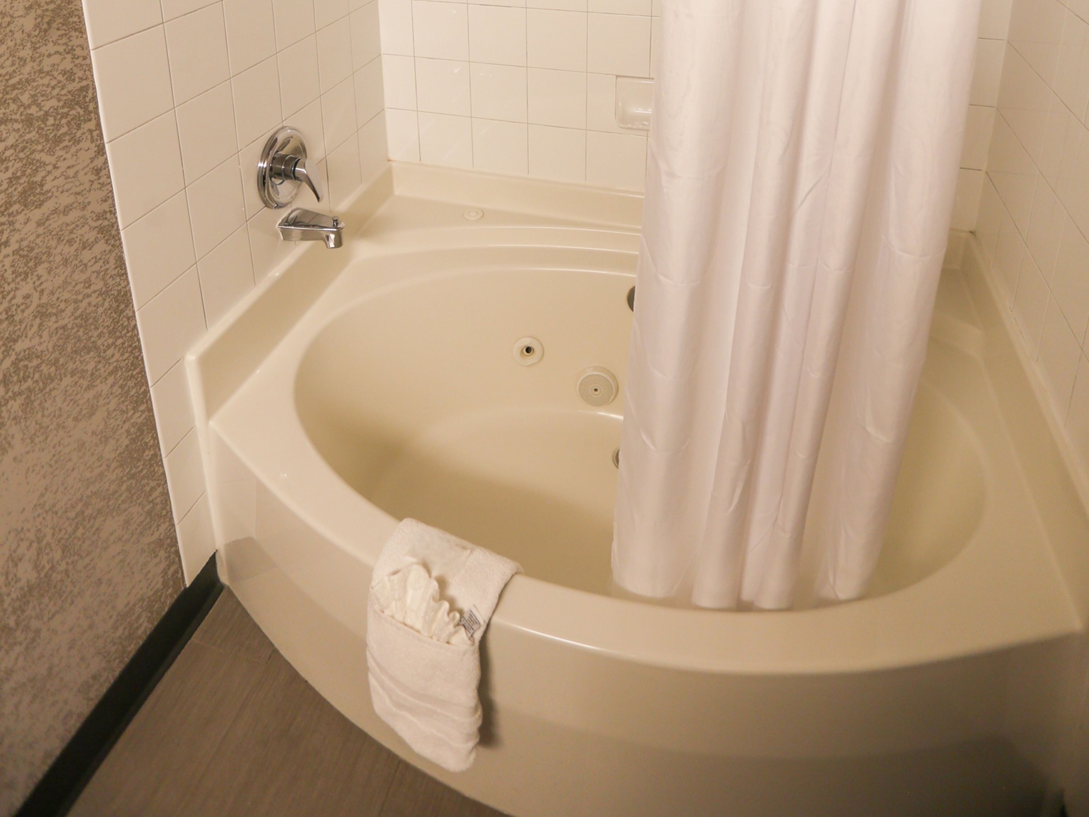A bathtub with a shower curtain, a towel, and a faucet.