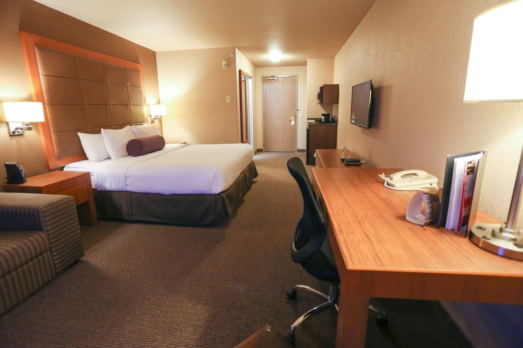 Habitació d'hotel amb llit, escriptori, cadira, televisió i telèfon.