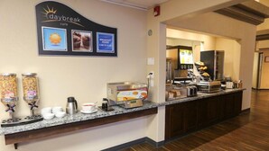 Un comptoir pour le petit-déjeuner équipé d’une machine à café, de distributeurs de céréales et d’un panneau indiquant les heures du petit-déjeuner.