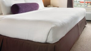 Une chambre d’hôtel avec un grand lit, une tête de lit, une lampe de chevet et une vue sur l’extérieur.