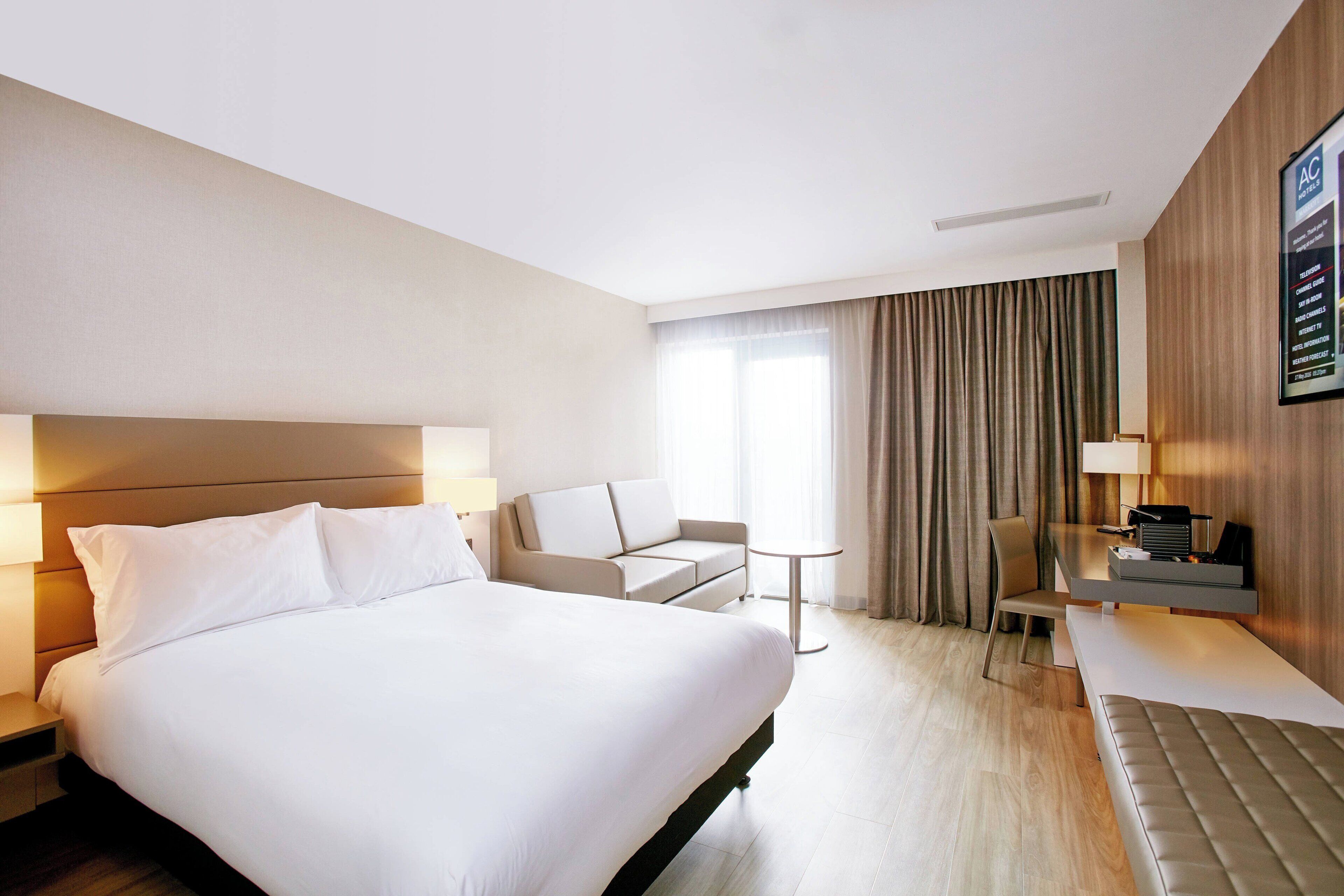 Une chambre d’hôtel moderne avec un grand lit, un canapé, une petite table et un bureau avec une chaise.