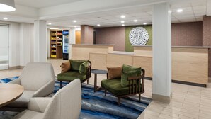 Un hall d’hôtel moderne, doté d’espaces aménagés avec des sièges, d’un comptoir de réception et d’une fontaine.
