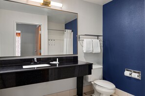Une salle de bain avec un lavabo au comptoir noir, des toilettes blanches et un mur bleu.
