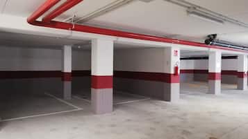 An empty parking garage with concrete pillars and red and white painted stripes.