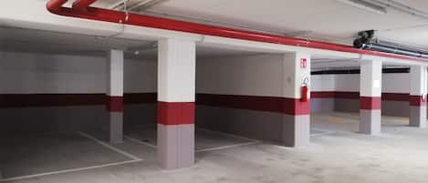 An empty parking garage with concrete pillars and red and white painted stripes.