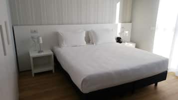 A neatly arranged hotel room with a large bed, a bedside table, a lamp, and a phone.