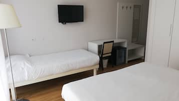 A hotel room with two single beds, a desk with a chair, a television, and a wardrobe.