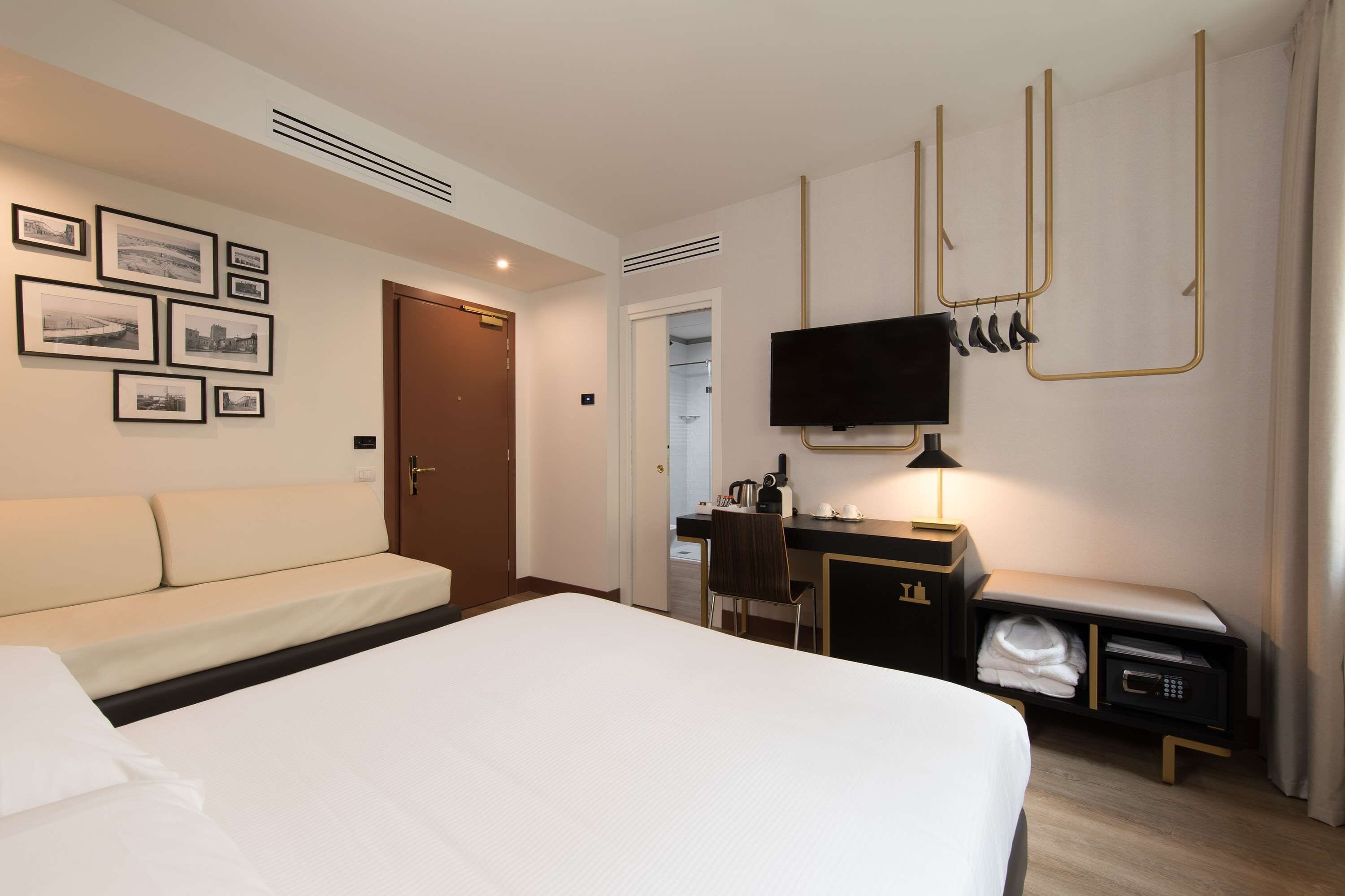 Une chambre d’hôtel avec un grand lit, un bureau avec une chaise, un téléviseur fixé au mur et un porte-manteau.