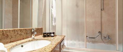 A bathroom with a marble sink, a glass-enclosed shower, and a large mirror.
