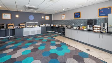 A breakfast area with a buffet setup, including various food items and a coffee machine.