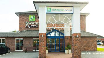 Een Holiday Inn Express gebouw met een bakstenen gevel, een grote glazen ingang en een blauw luifel.