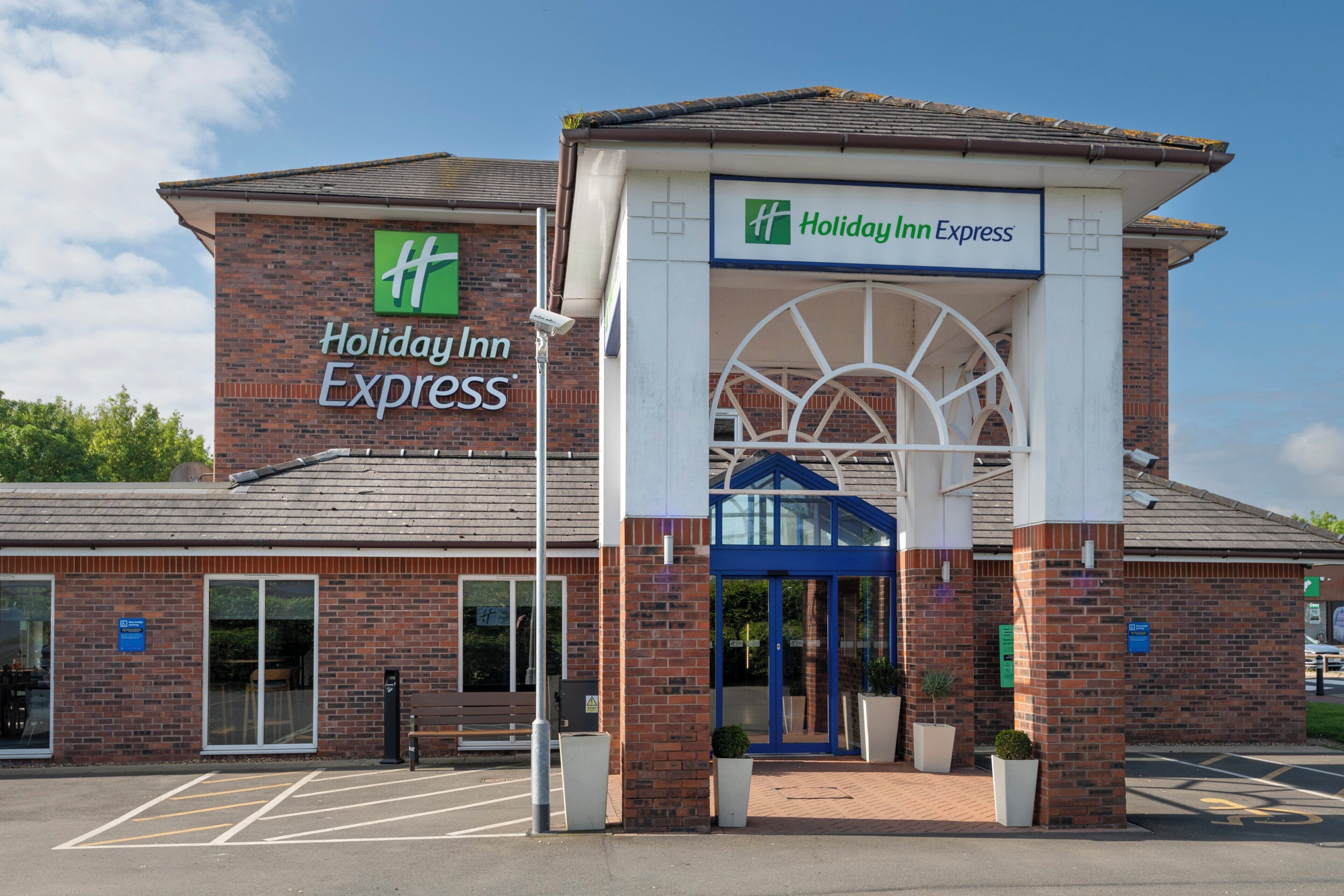 Een Holiday Inn Express gebouw met een bakstenen gevel, een grote ingang en een blauw dakoverhang.