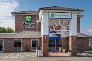A Holiday Inn Express building with a brick facade, large entrance, and a blue awning.