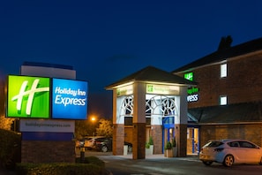 Um hotel Holiday Inn Express com uma placa de destaque, fachada de tijolos e entrada bem iluminada.