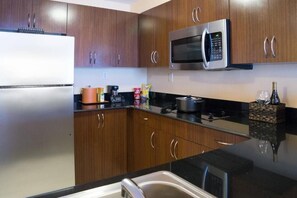 A kitchen with wooden cabinets, a stainless steel refrigerator, a microwave, and a gas stove.