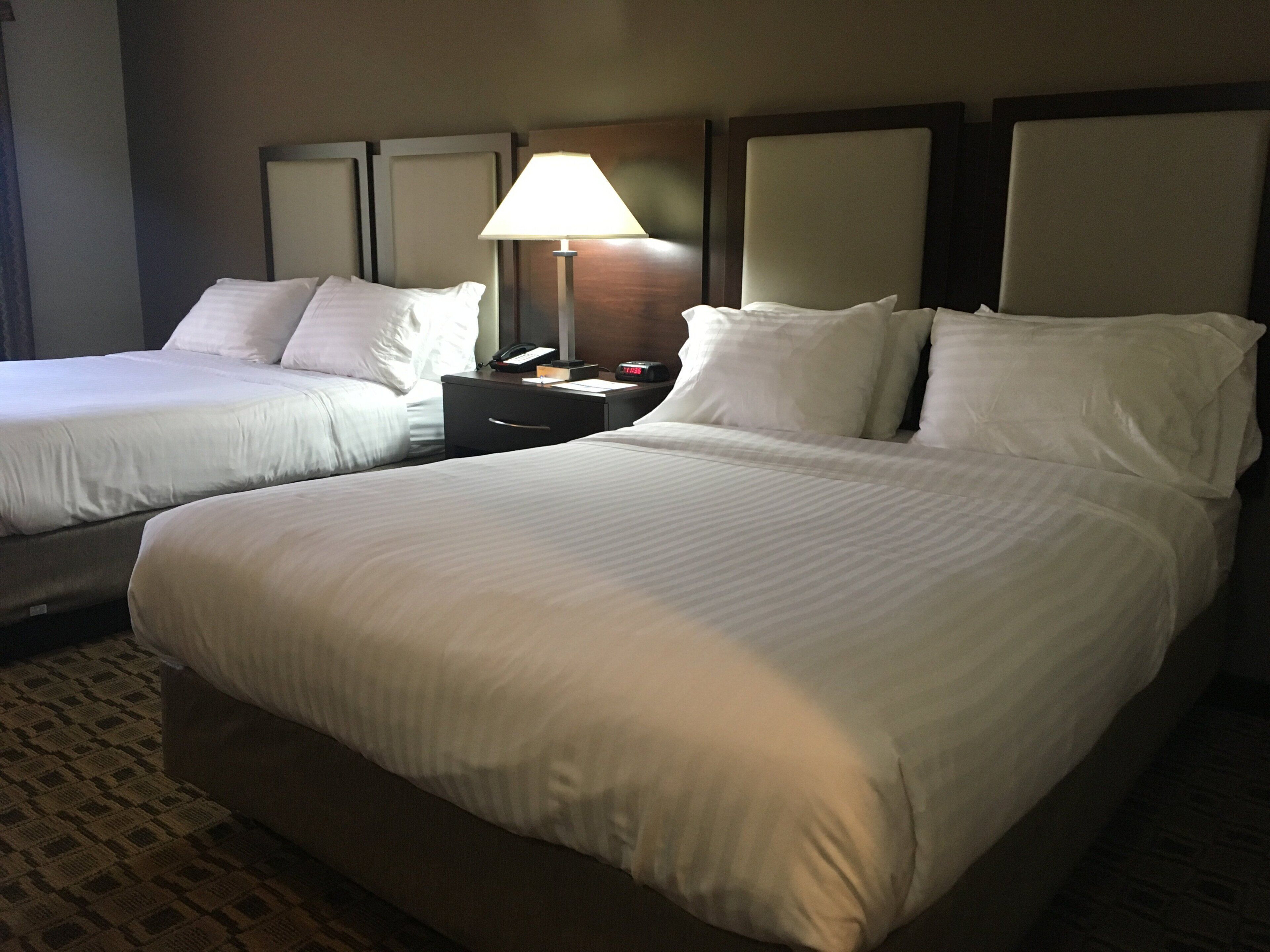 Una habitación de hotel con dos camas, una mesita de noche con lámpara y teléfono.