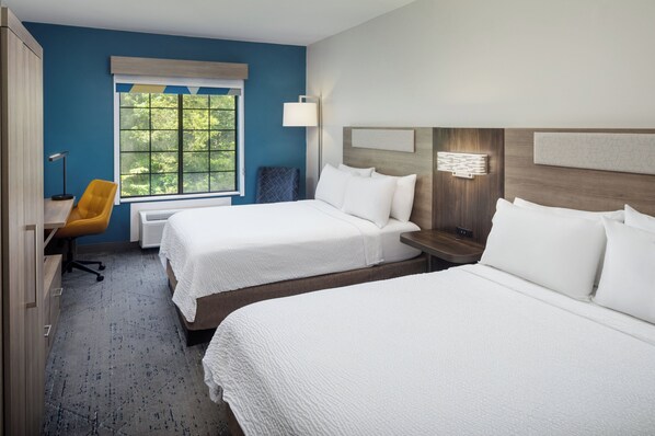 A hotel room with two beds, a desk, a chair, a window with a view of trees, and a wall-mounted lamp. - Holiday Inn Express & Suites Albermarle by IHG (Albemarle)