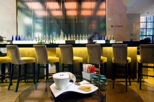 A bar area with a glass table, chairs, and a variety of bottles.