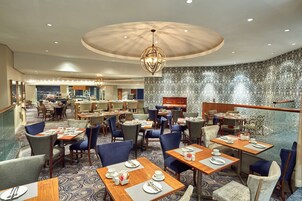 A spacious restaurant with multiple dining areas, including a bar and a seating area with a patterned wall.