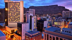 Paisagem urbana com um hotel em destaque chamado Southern Sun, apresentando um estilo arquitetônico moderno com vários andares e janelas iluminadas.